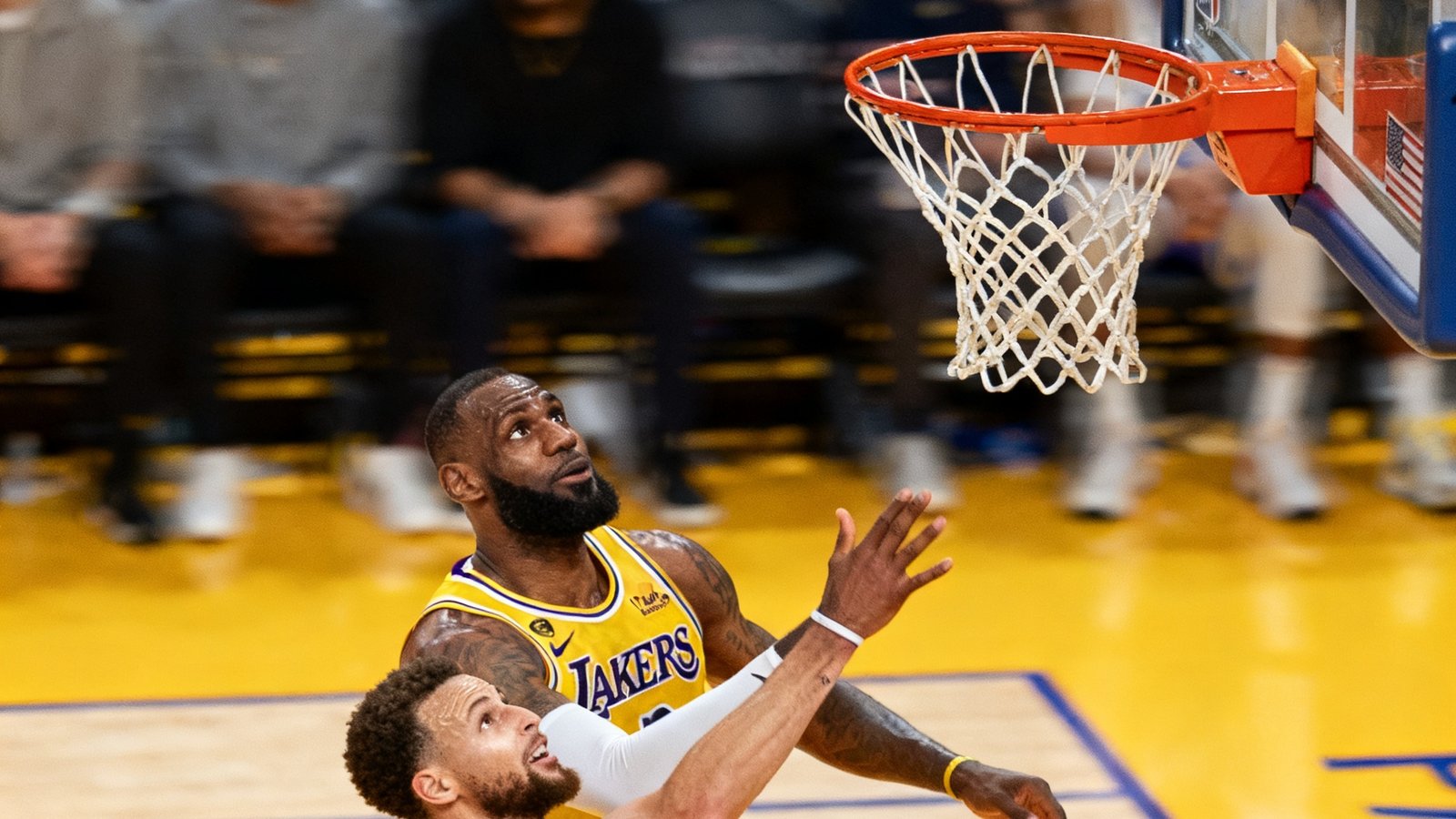 NBA焦点战末节最后两分钟，湖人球星詹姆斯在弧顶三分线外接球跳投命中关键三分，篮球在空中划出弧线即将穿网而过，勇士防守球员奋力扑防但为时已晚